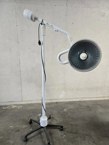 White adjustable midmark ritter surgical lamp with circular head and black wheeled base for minor surgery procedure