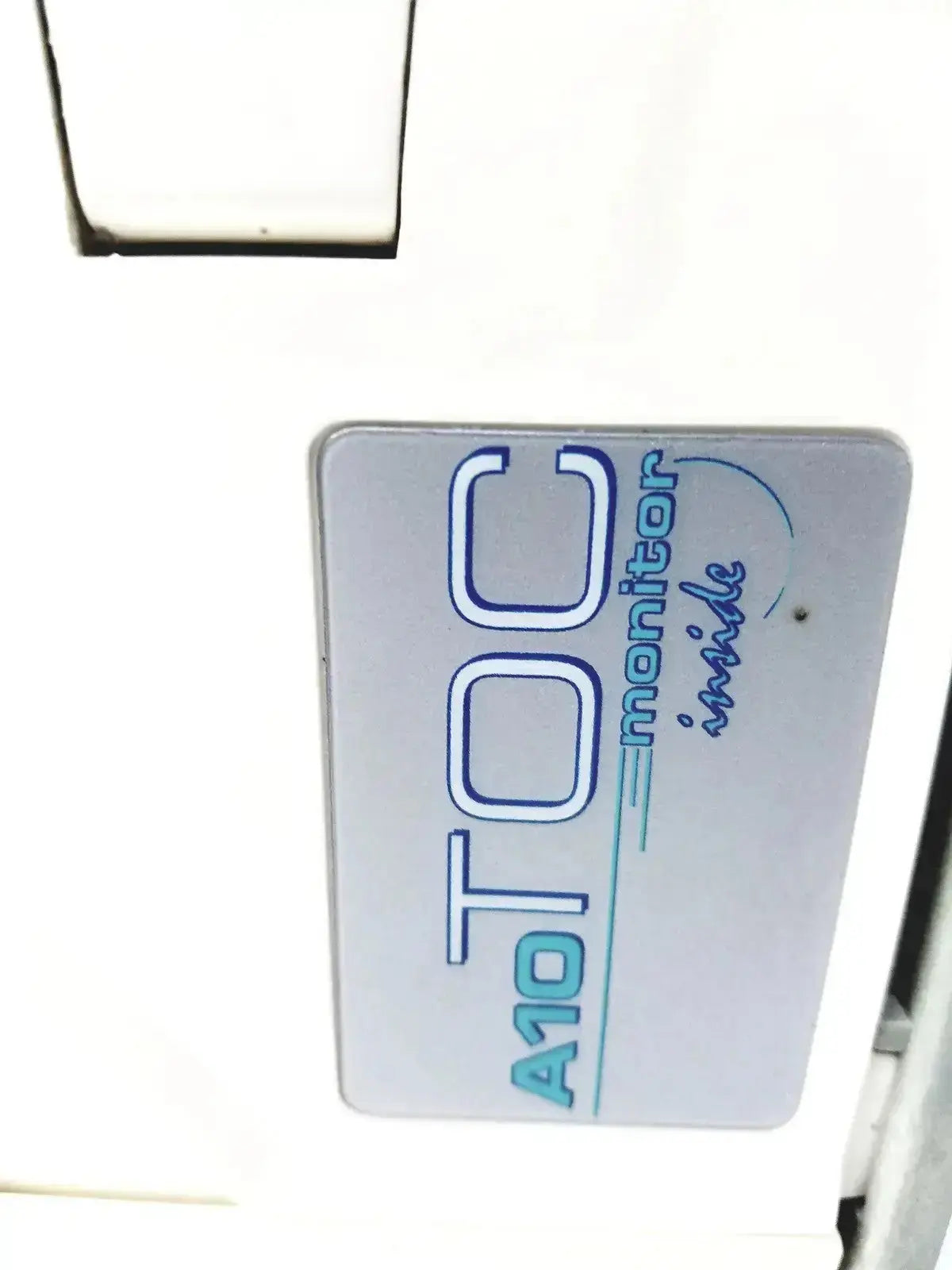 A sleek white rectangular label with blue lettering reading a10 toc monitor inside on millipore milli-q advantage a10 toc system