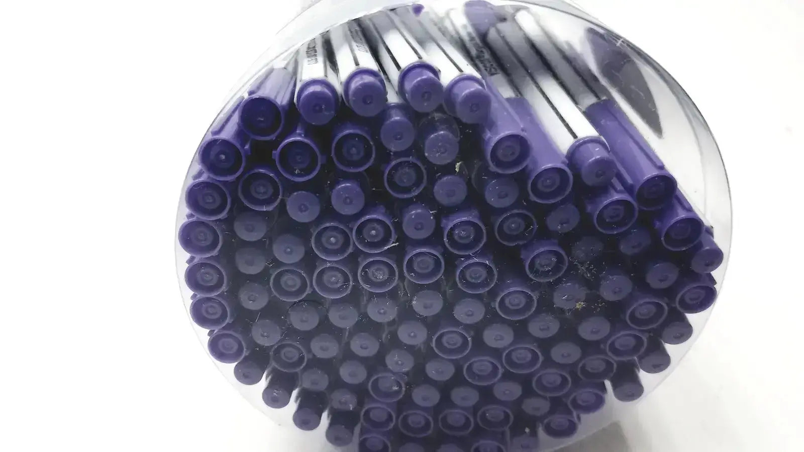 A clear plastic container filled with purple mini pre-surgery skin markers featuring scurb resistant ink