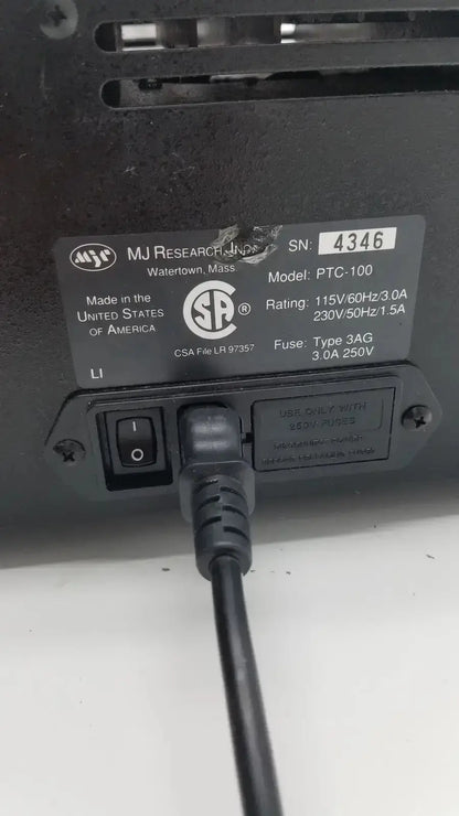 Black plastic power cord with plug inserted into on off switch and labeled specifications plate on back of mj research ptc-100 programmable thermal controller