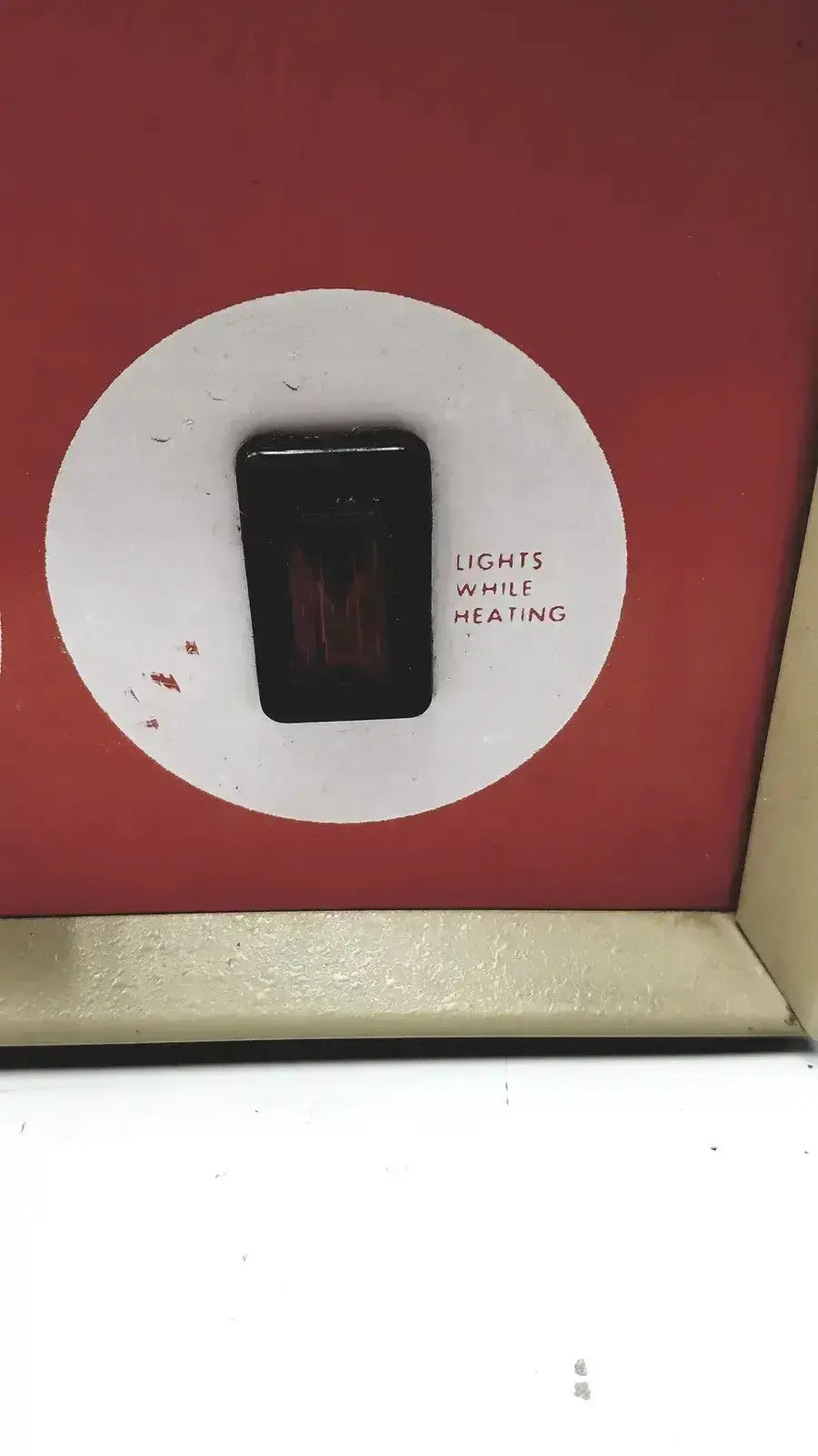 Black rectangular toggle switch on a white circular label set against a red background for napco national appliance water bath