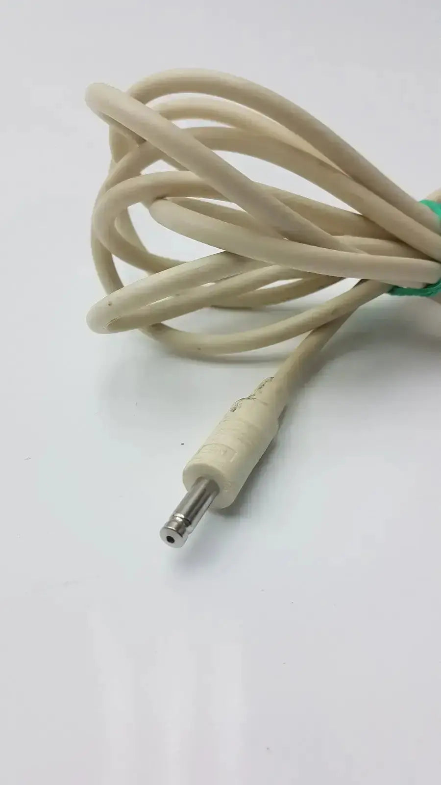Beige nbp sensor probe cable with straight metallic barrel connector and green tie securing the coiled cord
