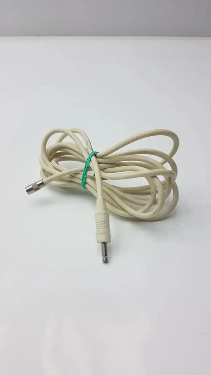 A coiled beige nbp sensor probe cable with a green tie and two metallic straight plug connectors