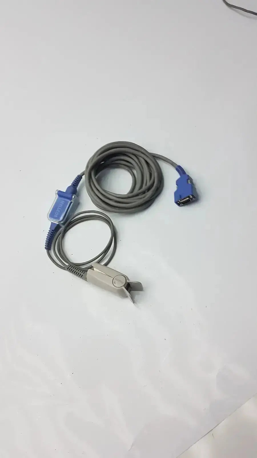 Gray coiled extension cable with blue connectors and silver pulse oximeter finger clip for used medical equipment sale