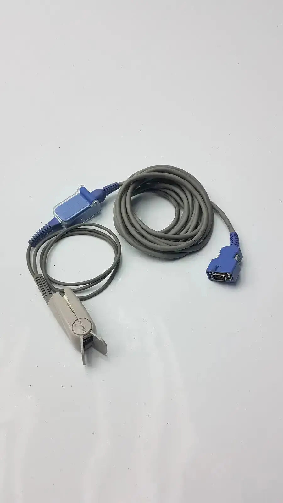 Gray coiled extension cable with blue connectors and silver pulse oximeter finger clip used medical equipment for sale