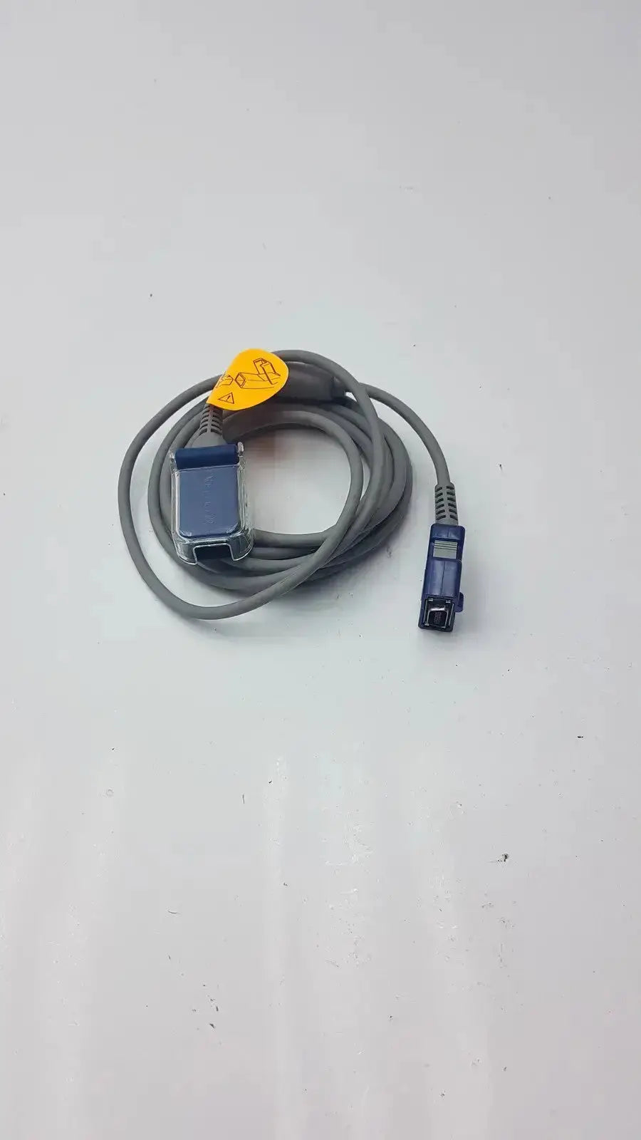 Nellcor pulse oximetry interface cable doc-10 gray coiled with blue connectors and yellow warning label for accurate monitoring