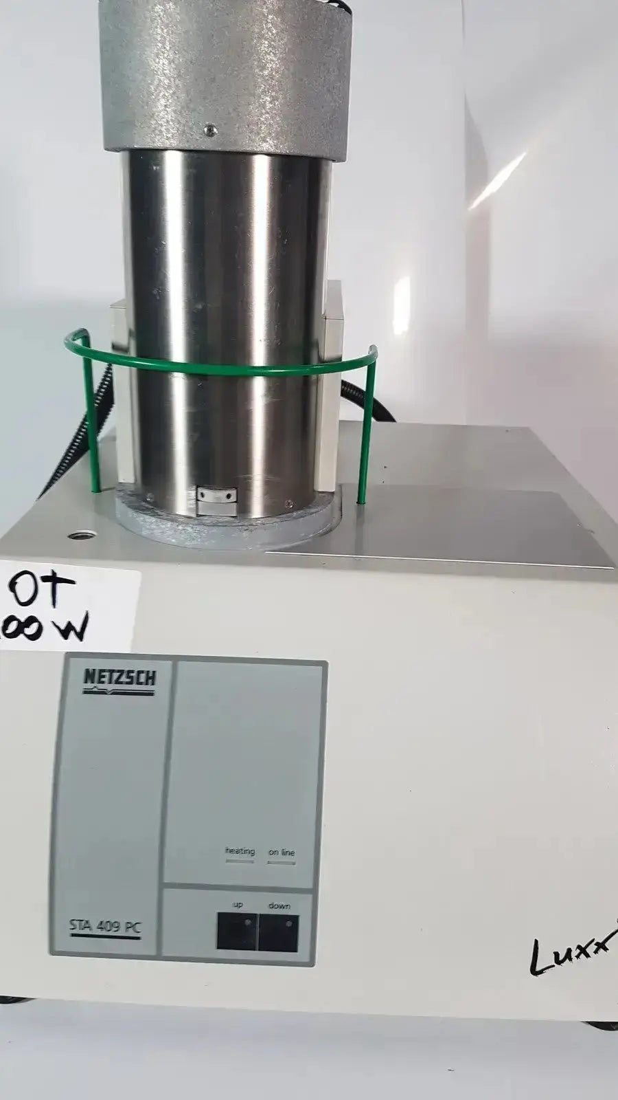 Silver metallic cylindrical heating chamber with green protective ring on white netzsch sta 409 pc simultaneous thermal analyzer