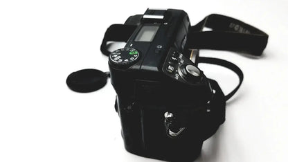 Black Nikon Coolpix E8400 digital camera with matte finish, visible dials, buttons, lens cap, reliable monitoring features