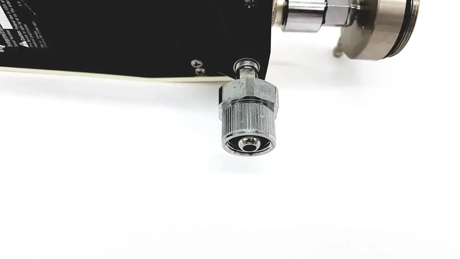 Silver metallic threaded connector with hexagonal nut and flanged end attached to black industrial component of ohmeda ffa19643 intermittent unit
