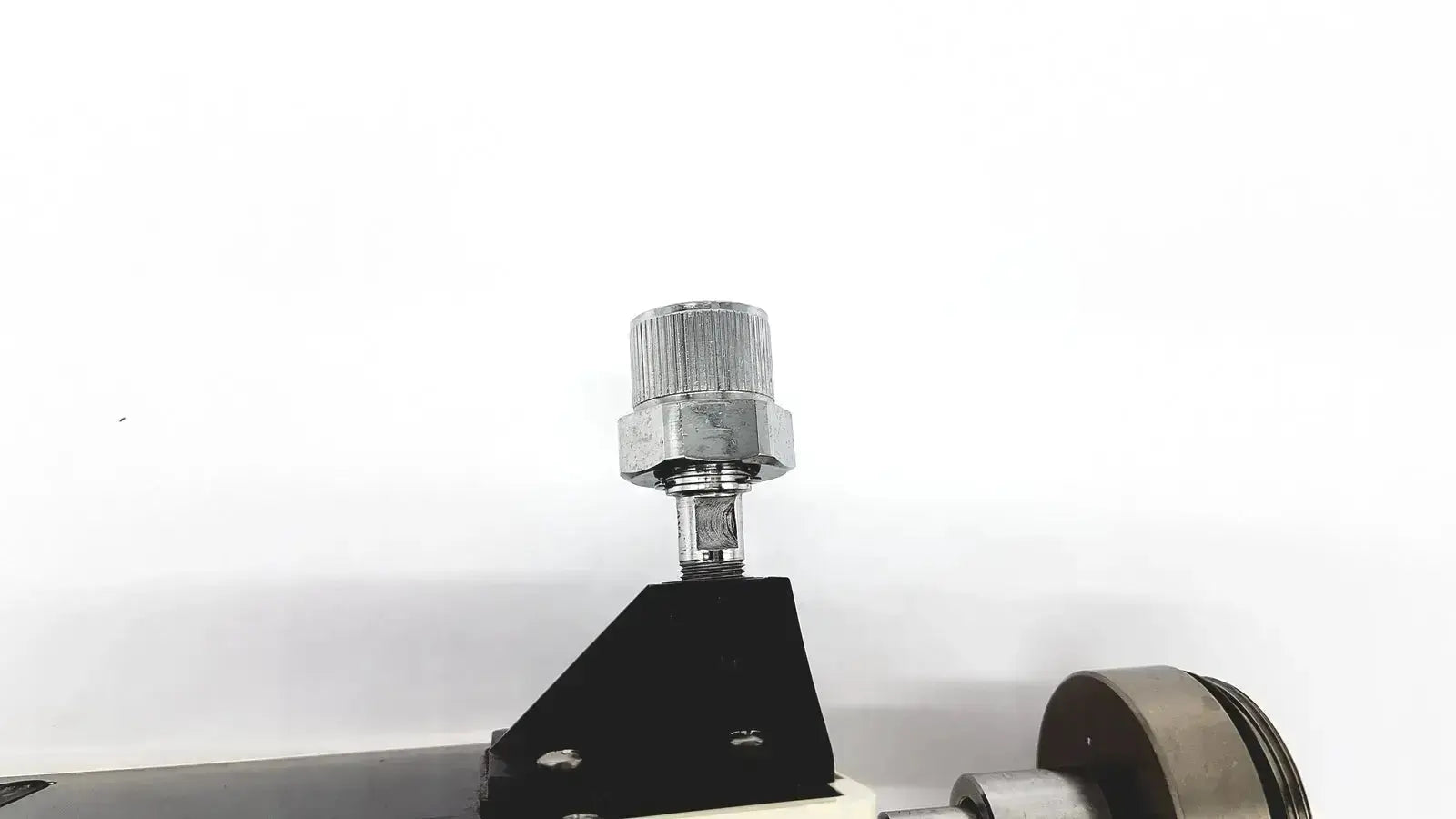 Silver knurled knob on a hexagonal nut mounted on a black triangular base of ohmeda ffa19643 intermittent unit