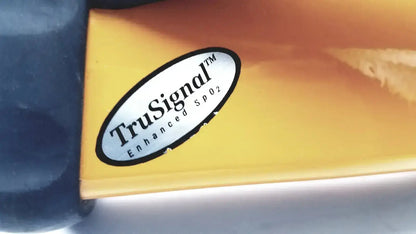 A white oval sticker with black text reading trusignal enhance spo2 affixed to a glossy orange surface of an ohmeda trusat oximeter