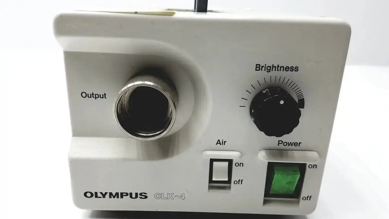 White Olympus CLK-4 halogen light source with metallic output port and black control knobs for brightness air and power