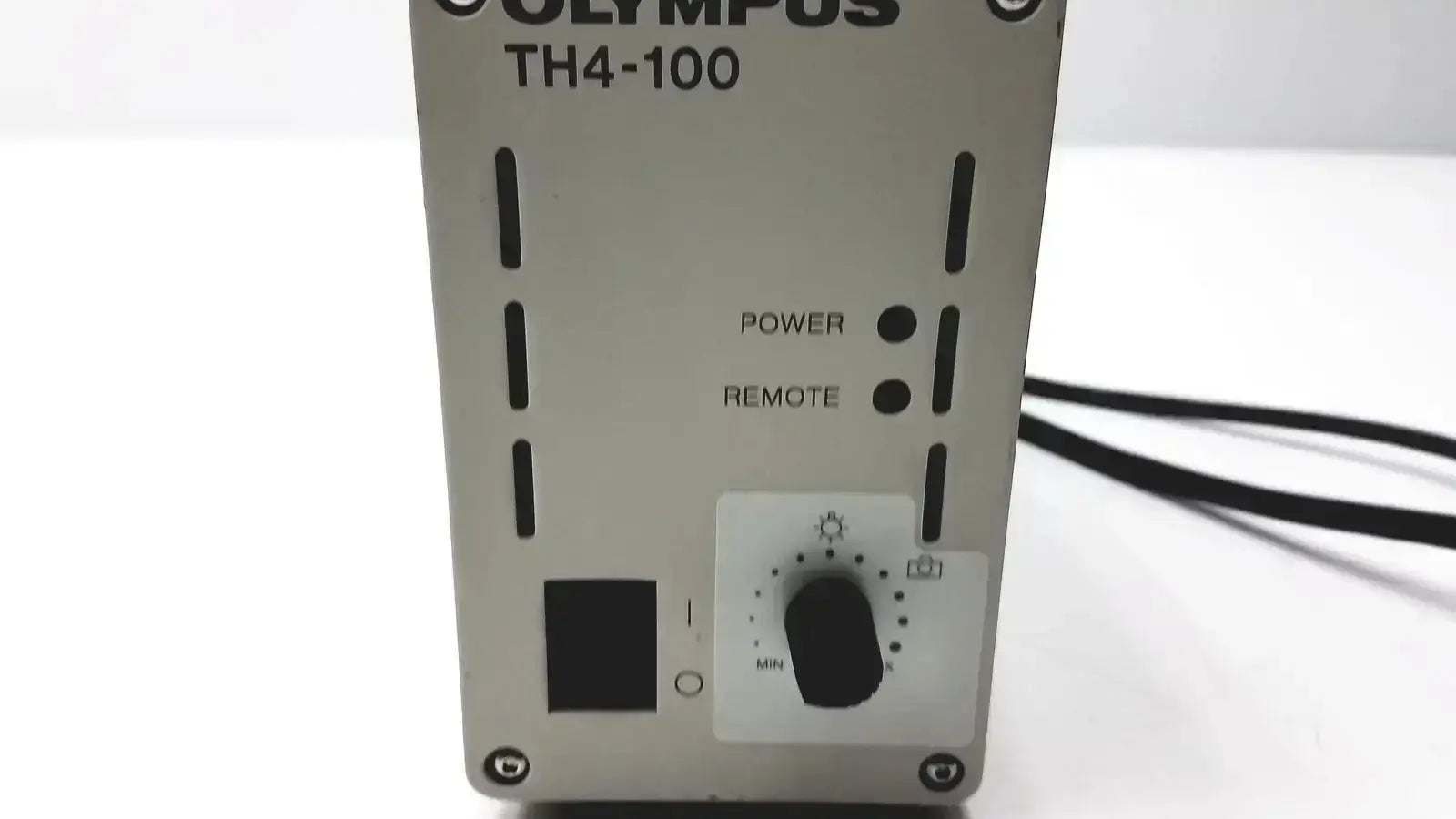 Silver olympus th4-100 camera flash unit with black power and remote buttons and white dial for halogen power supply