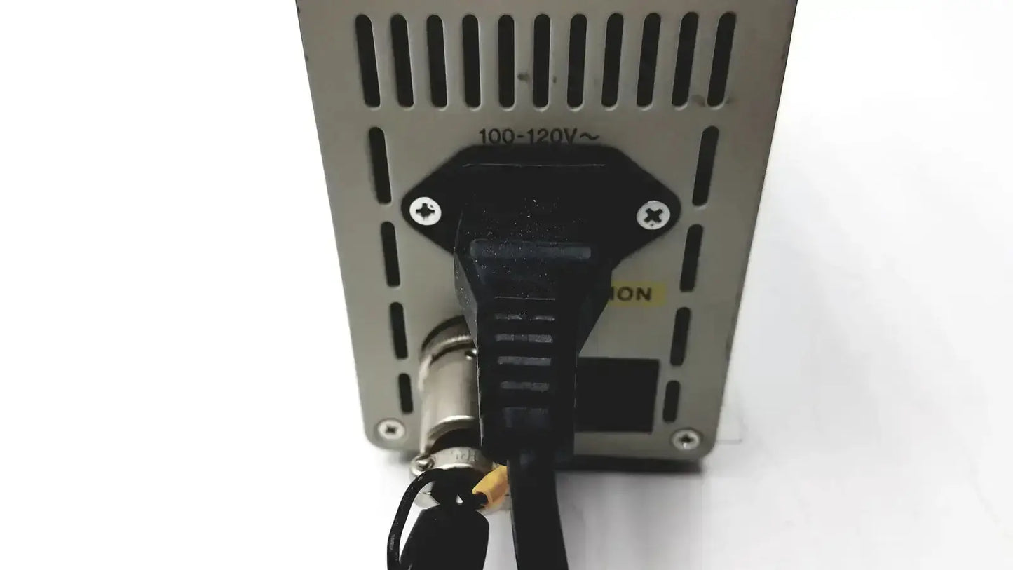 Black power cord plugged into silver metal olympus th4-100 halogen power supply unit with ventilation slots and voltage markings