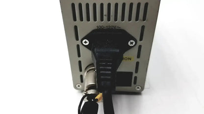 Black power cord plugged into silver metal olympus th4-100 halogen power supply unit with ventilation slots and voltage markings