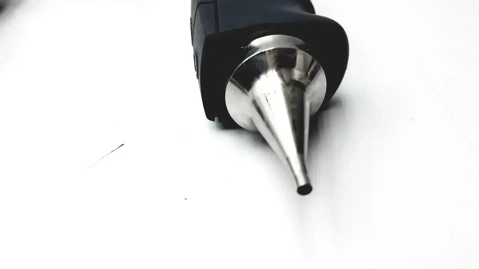 Black-handled glue gun with shiny metallic nozzle alongside otocam 973530 video otoscope for hearing care evaluation