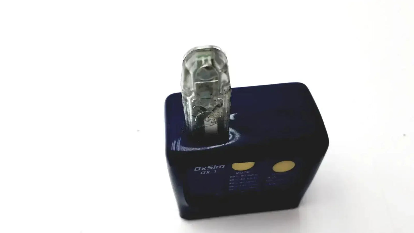Clear plastic usb drive inserted into black charging dock with gold buttons on oxsim OX-1 pulse oximeter simulator