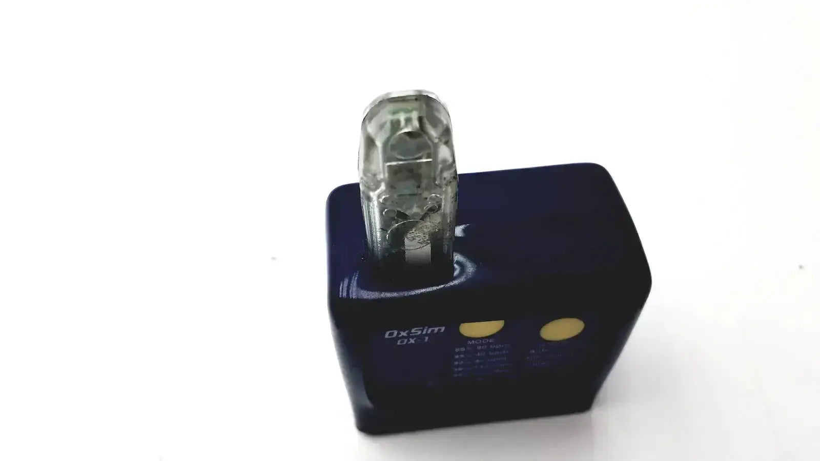 Clear plastic usb drive inserted into black charging dock with gold buttons on oxsim OX-1 pulse oximeter simulator