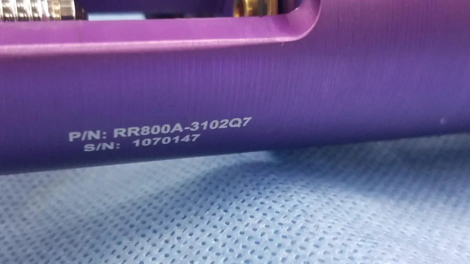 Purple cylindrical oxygen regulator with engraved part and serial numbers for precise medical gas flow control