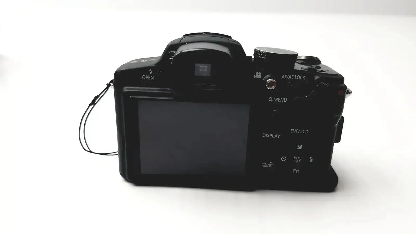 Black Panasonic model DMC-FZ35 digital camera with textured grip and visible control dials with Lumix battery charger