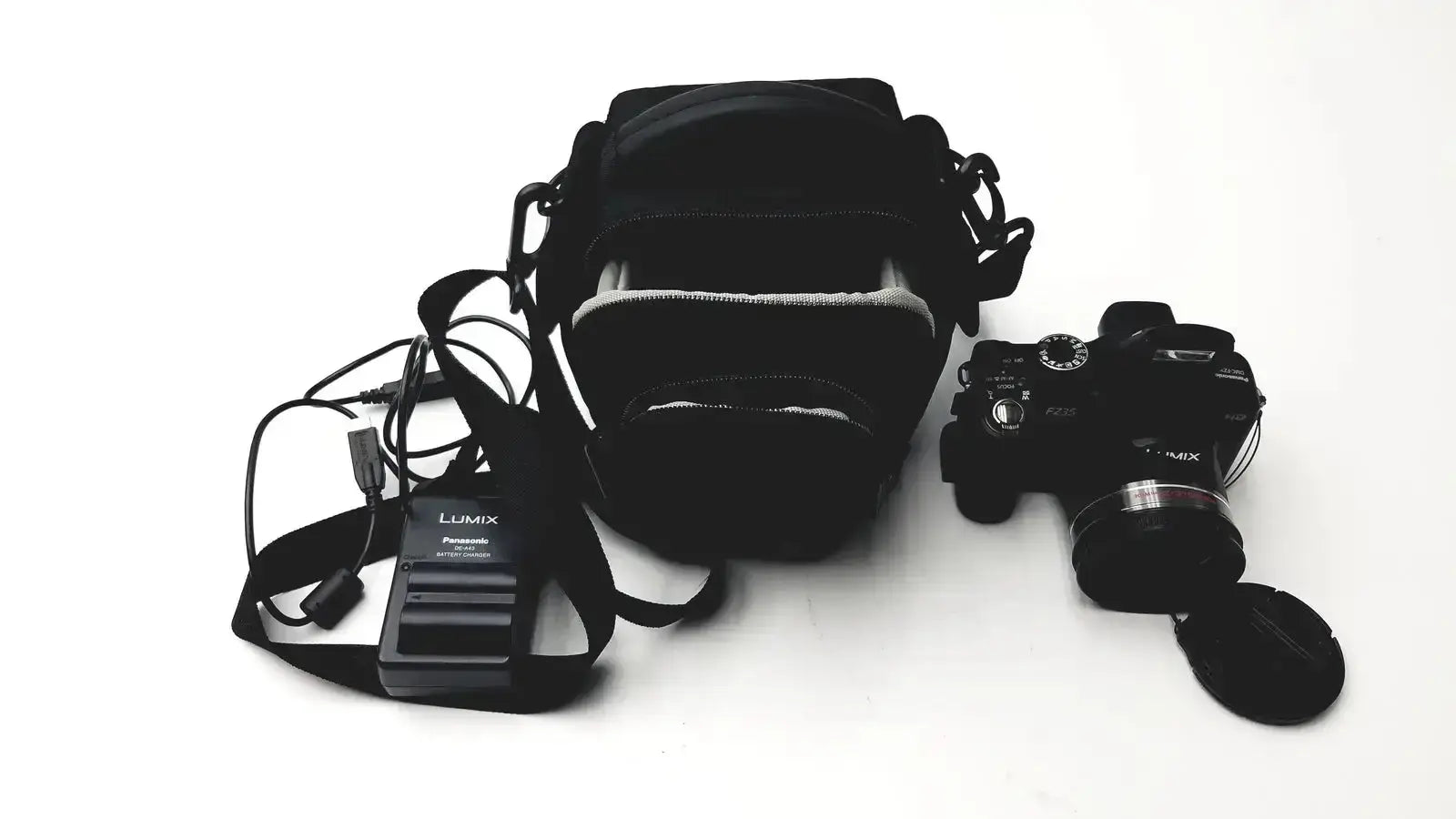 Black Panasonic model DMC-FZ35 digital camera with attached lens cap and carrying case alongside battery charger