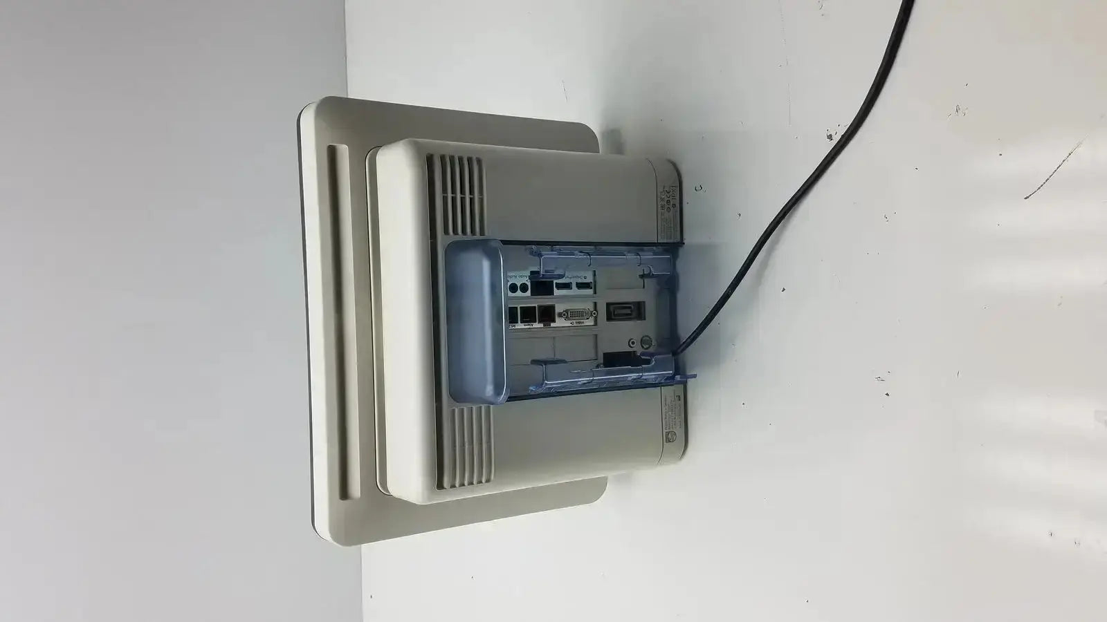 Beige plastic intellivue mx700 bedside patient monitor showing blue internal component and black cable connected