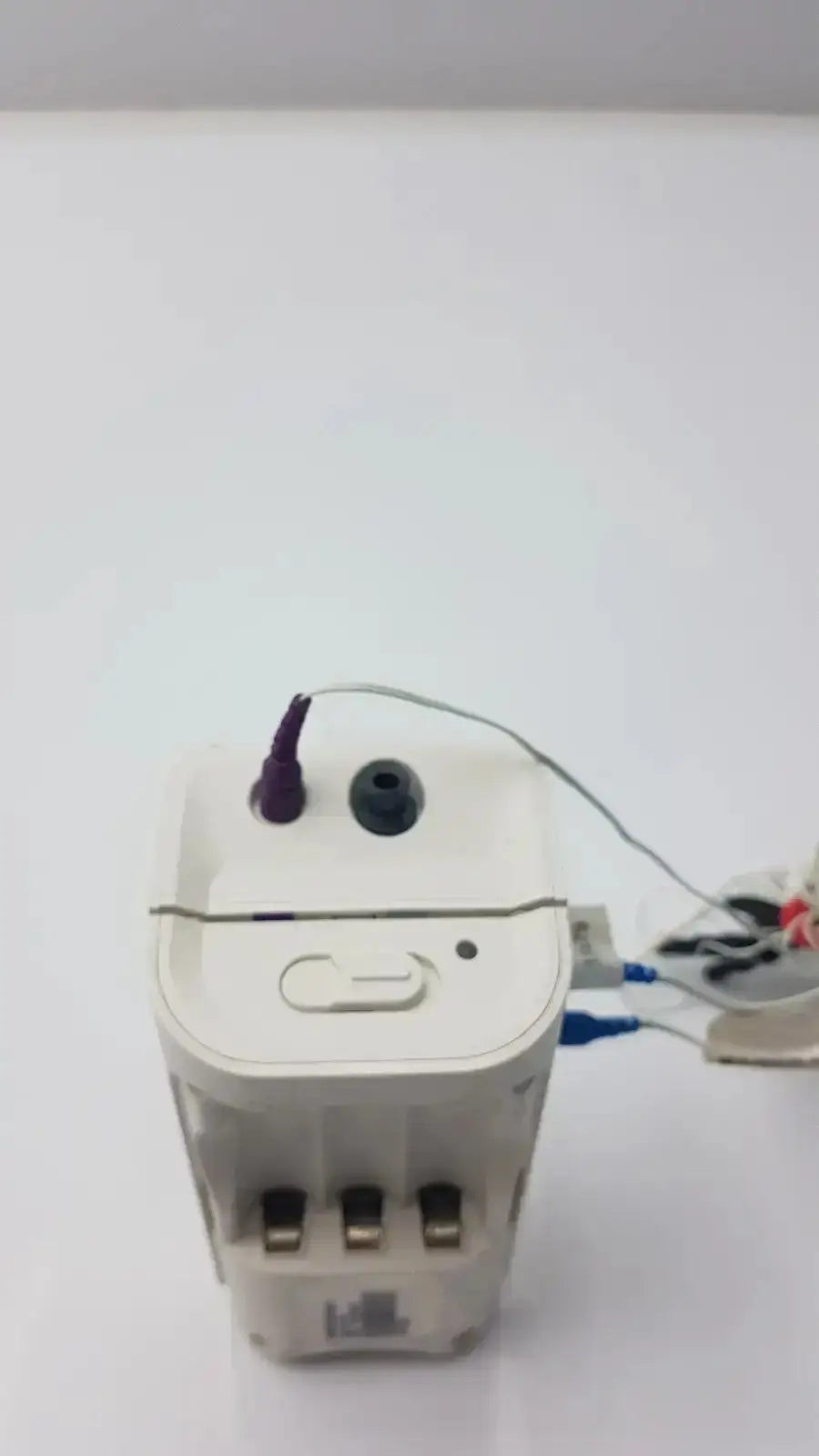 White rectangular philips healthcare respiironics aliice pdx electronic device with gold prongs and blue cables attached