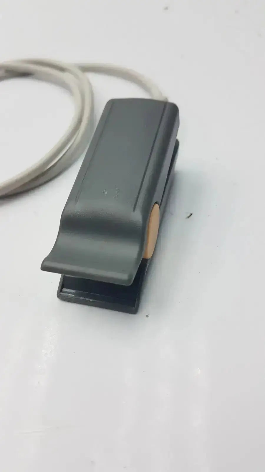 Black plastic foot pedal with beige button on the side of philips m1196t reusable adult spo2 clip sensor connector