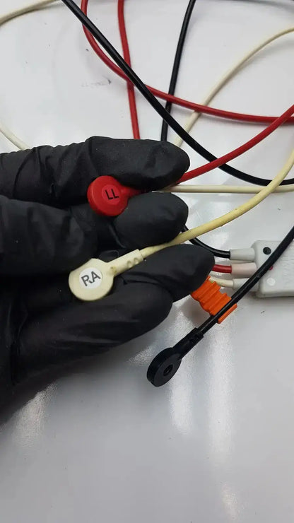 A hand in black gloves holds philips m1673a 3 leadset snap with trunk cable featuring red and beige connectors