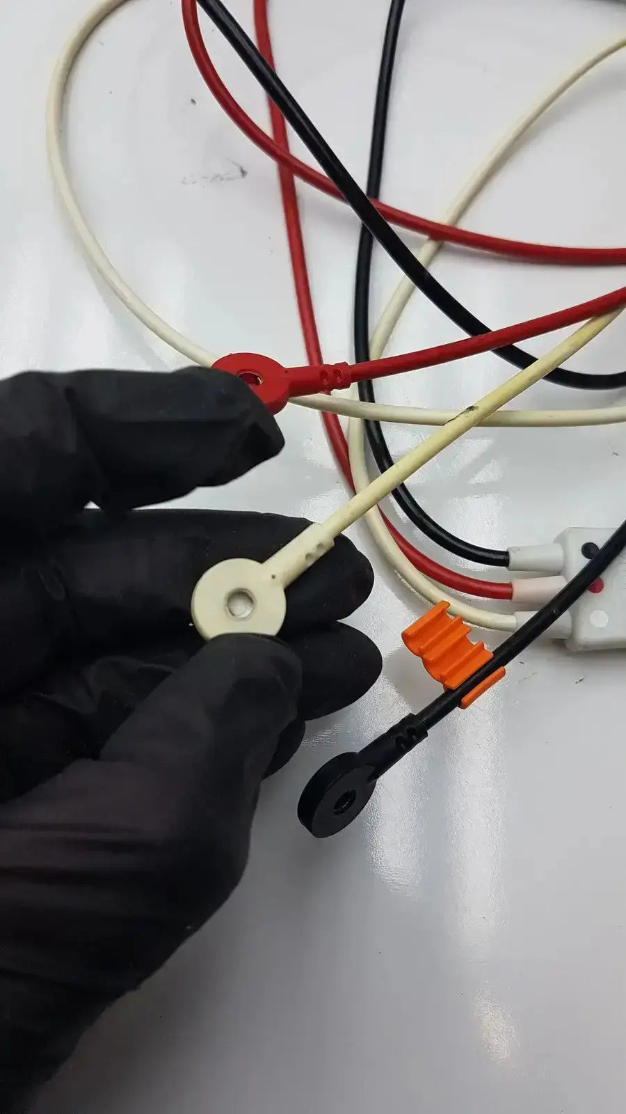 White plastic connector with circular hole and red terminal on coiled trunk cable for Philips M1673A leadset ICU use