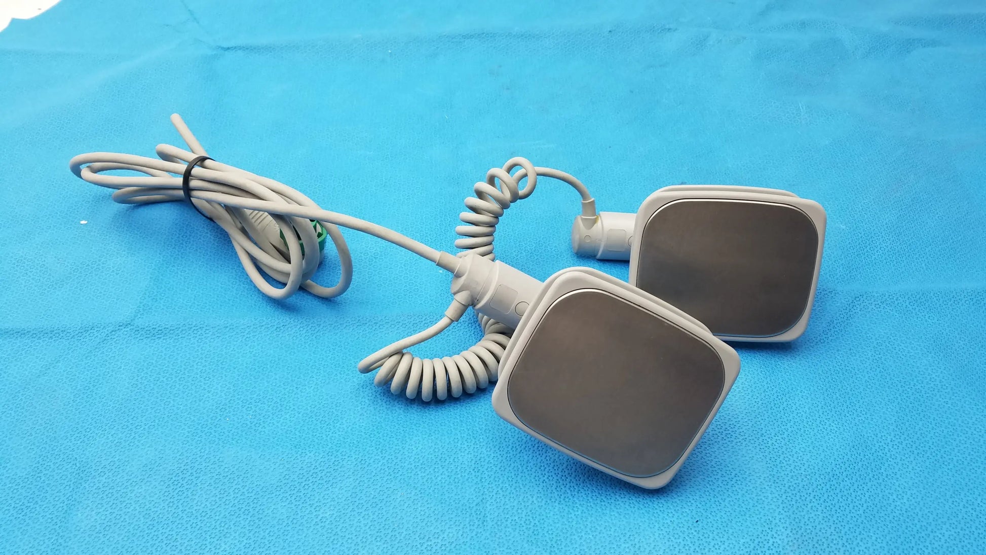 Gray square-shaped medical equipment pads with coiled gray cables philips m3543a water resistant external hard paddles