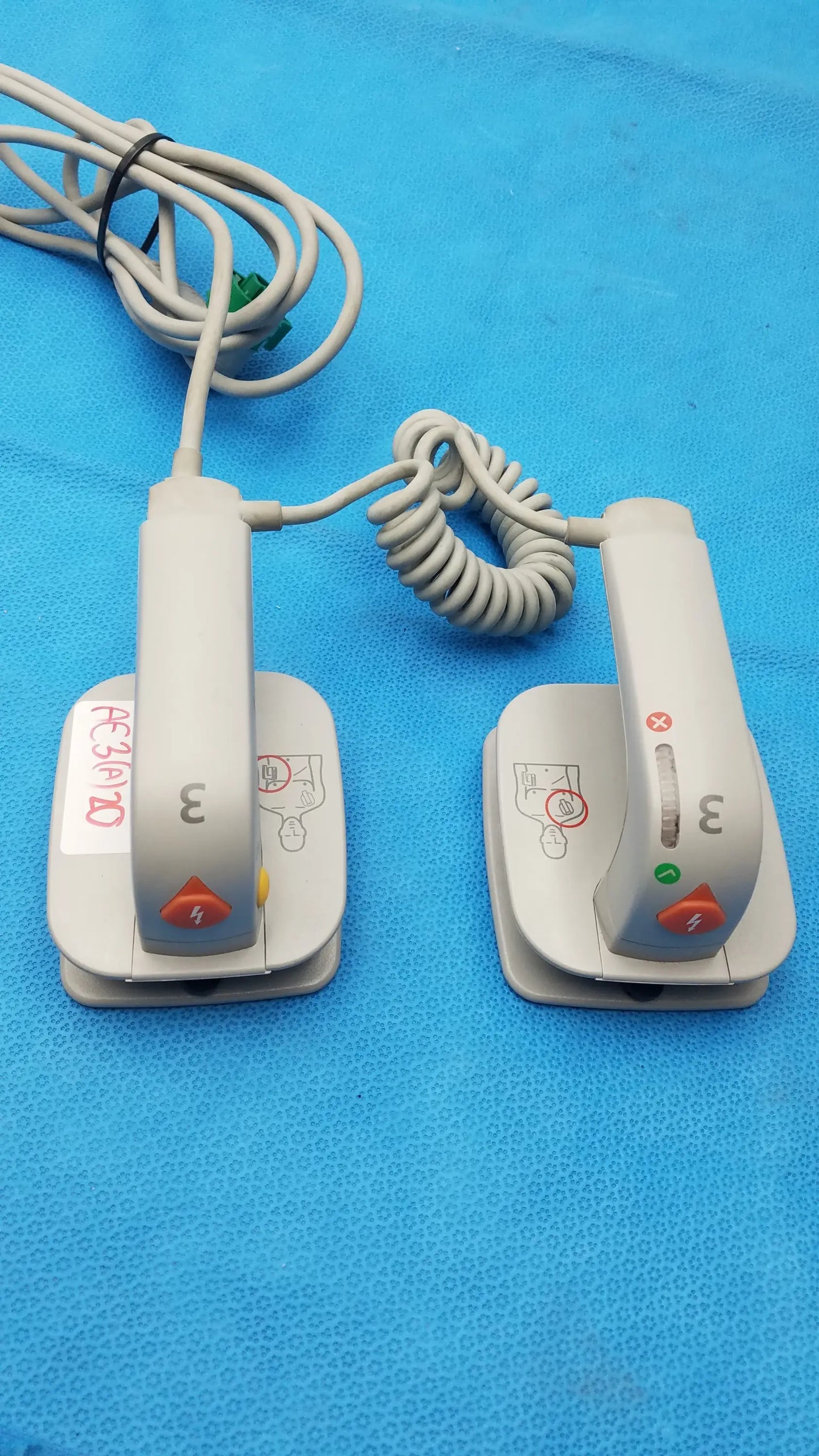 White plastic philips m3543a water resistant external hard paddles with coiled gray cords and orange emergency buttons medical equipment