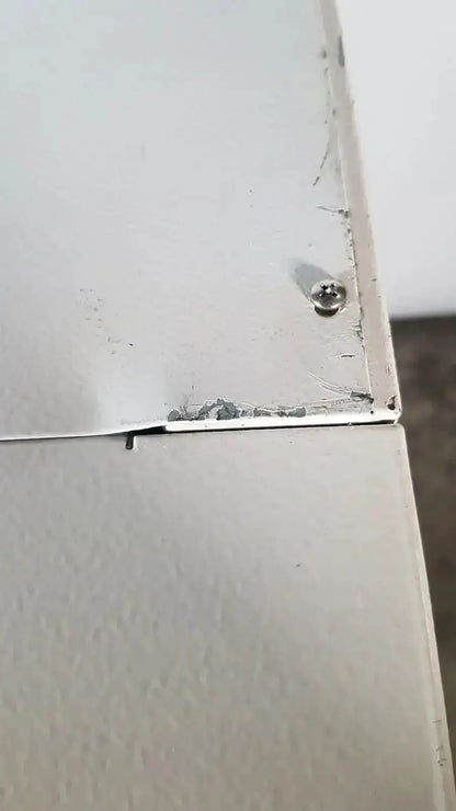 A worn light gray metal panel with chipped paint and a screw on the back side of a precision napco series co2 incubator