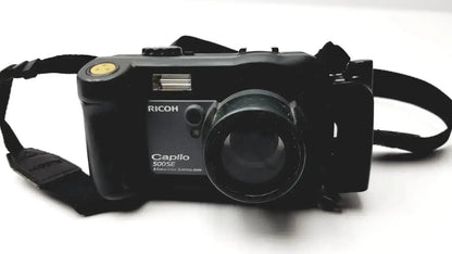Black Ricoh Caplio 500SE digital camera with 8.0 mega pixels and yellow shutter button featuring 3x optical zoom digital lens