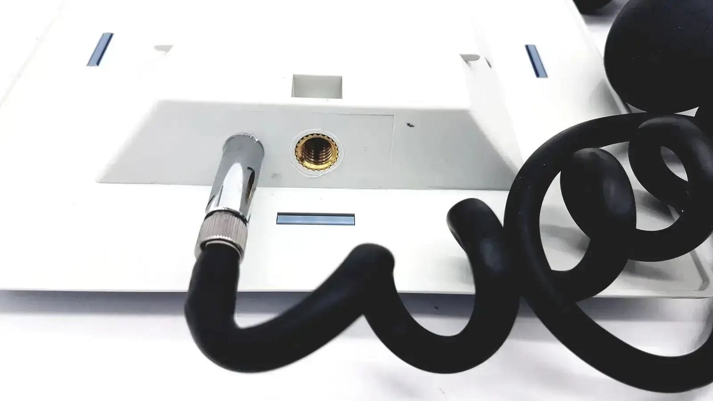 Black coiled telephone cord with metallic connector attached to white riester big ben square sphygmomanometer device