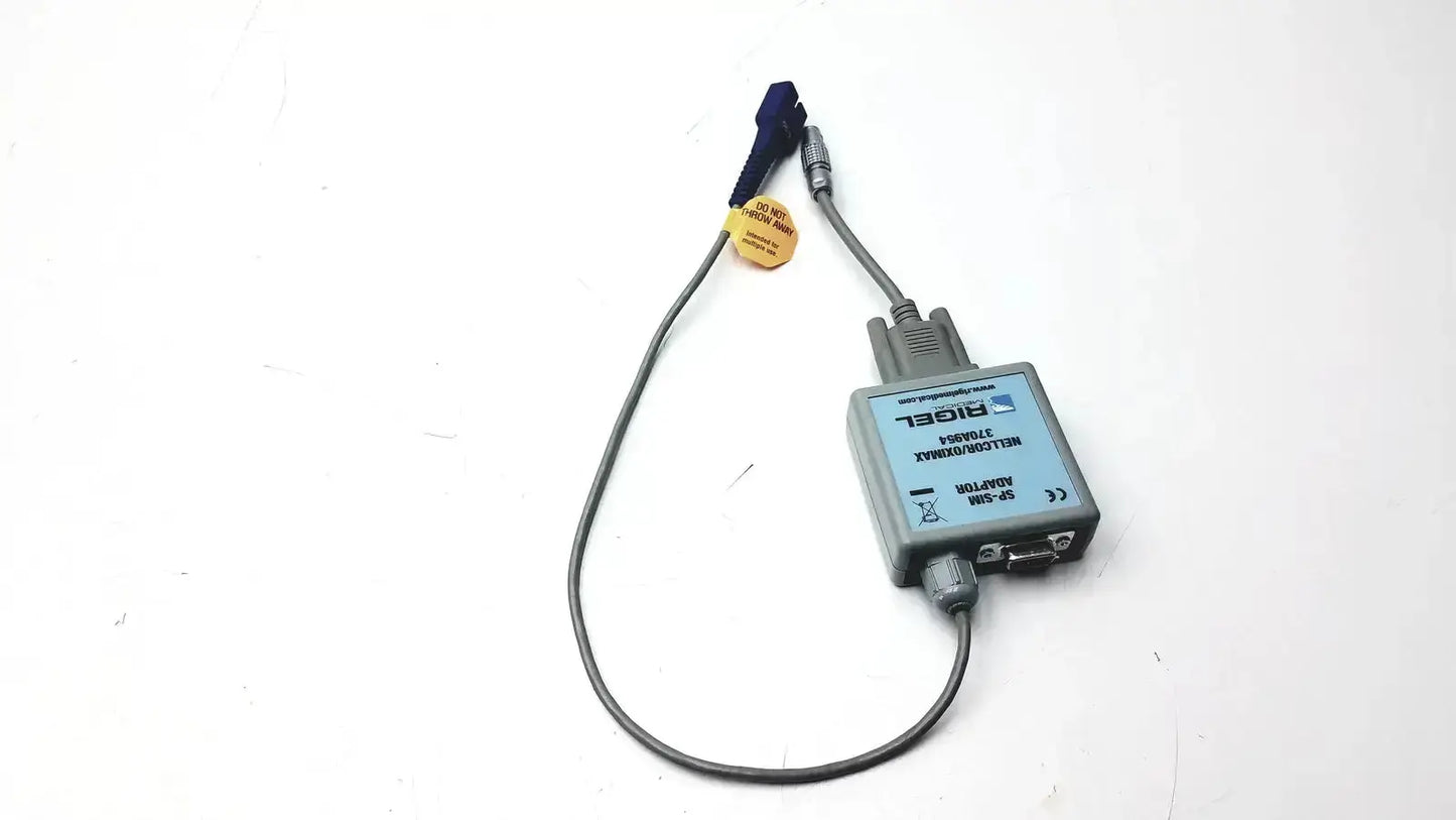 Gray rectangular digital rigel medical adapter nellcor oximax with blue connector and gray cables labeled digel on surface