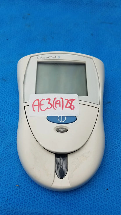 White roche coaguchek s medical equipment with small rectangular screen and blue button for reuse medical monitoring