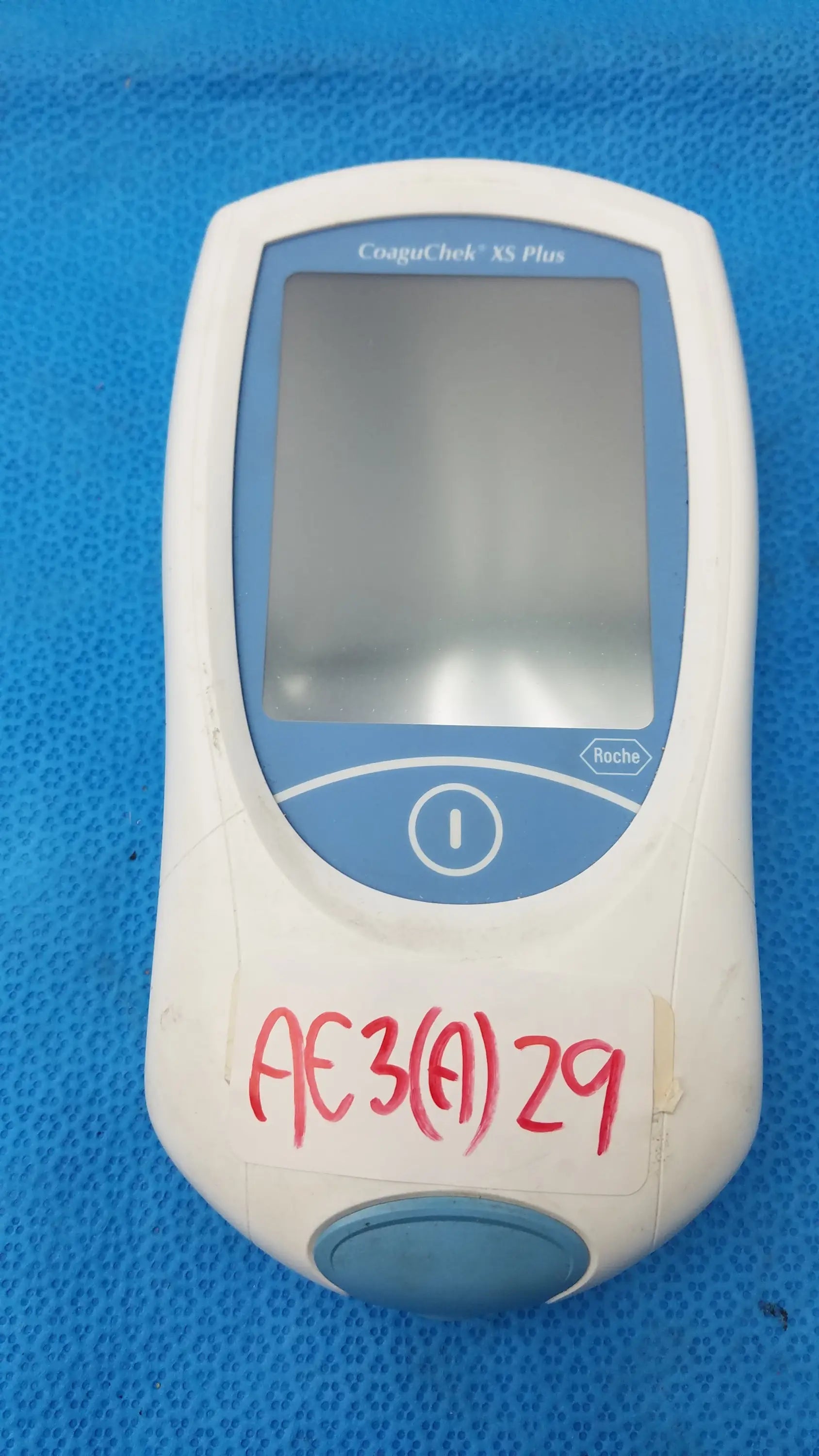 White and blue Roche CoaguChek XS Plus coagulation meter featuring a rounded rectangular design and Roche logo medical equipment