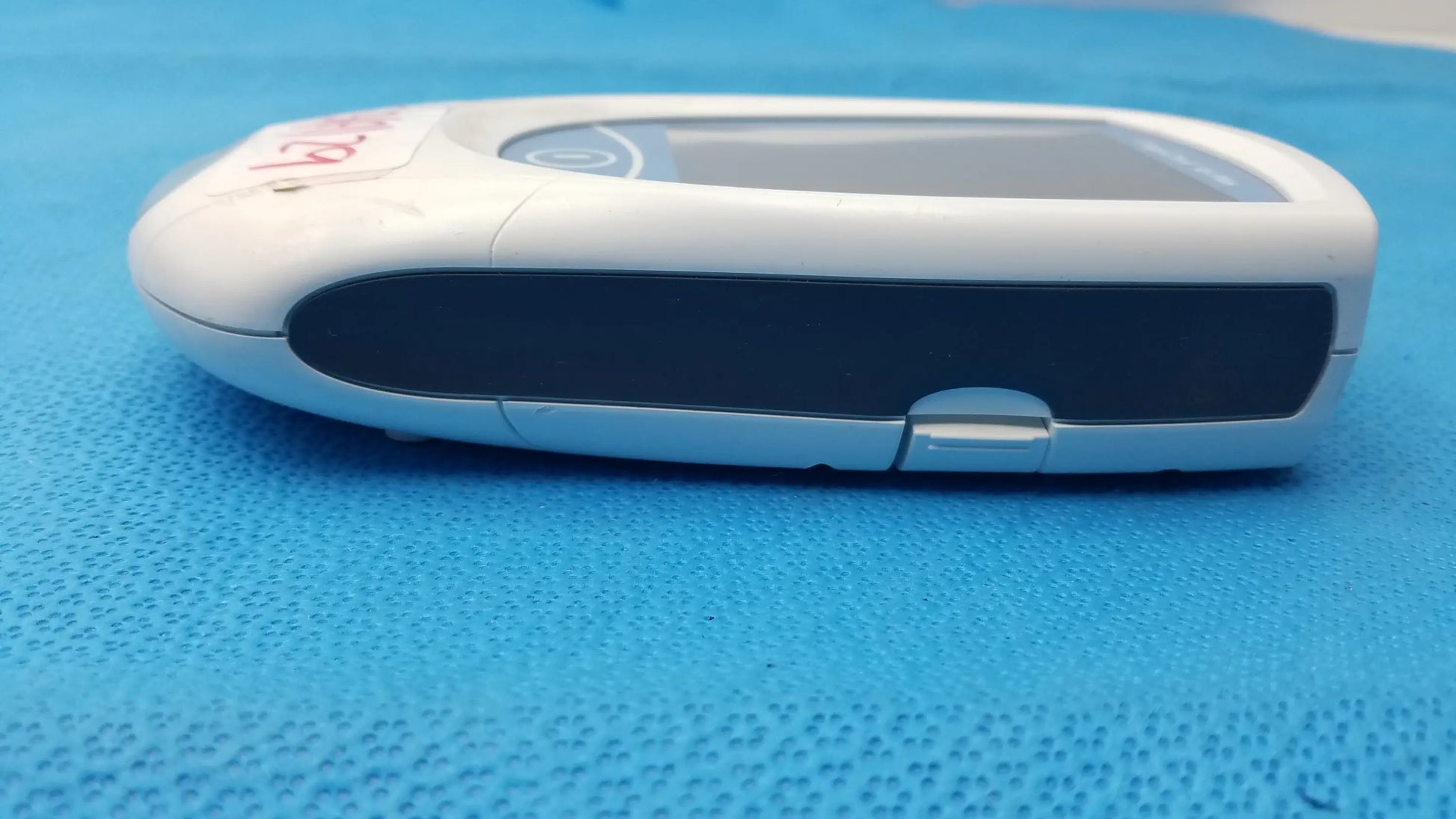 White plastic roche coaguchek xs plus coagulation meter with black accent strip and silver button for medical equipment use