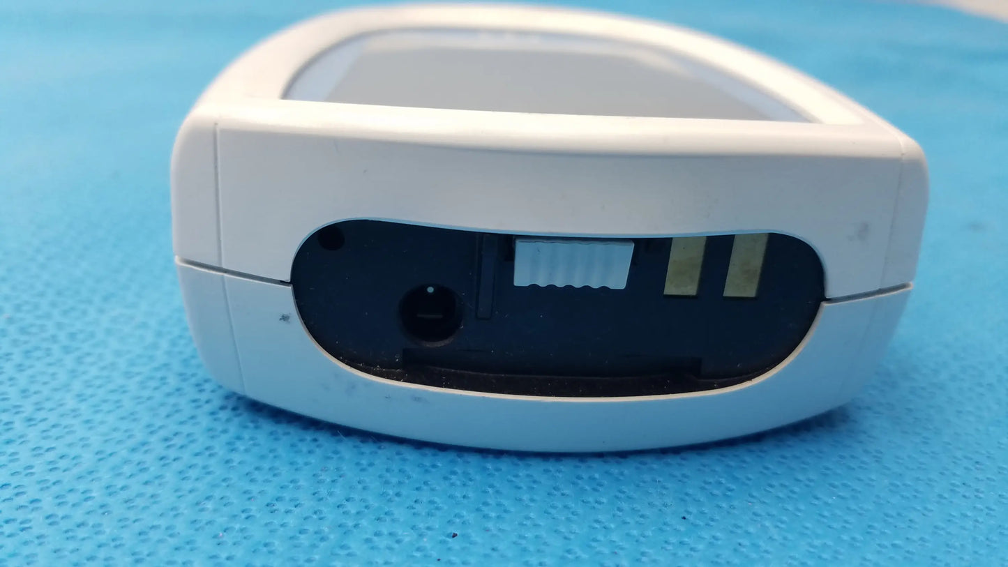 White plastic roche coaguchek xs plus coagulation meter with black interior housing and visible sensor slots medical equipment