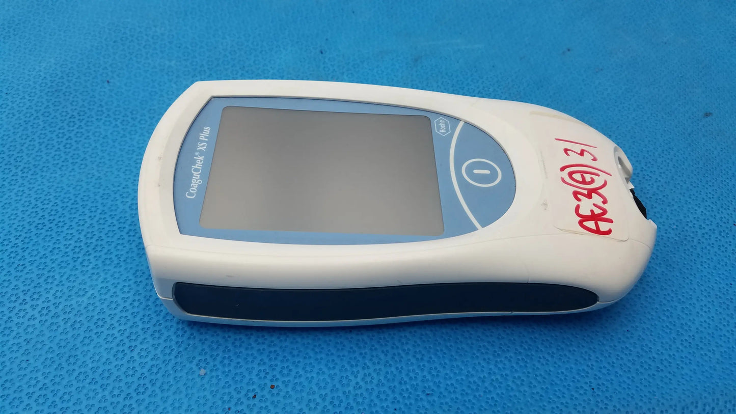 Roche coaguchek xs plus handheld medical equipment with white and blue body, rectangular screen, and circular button on right side