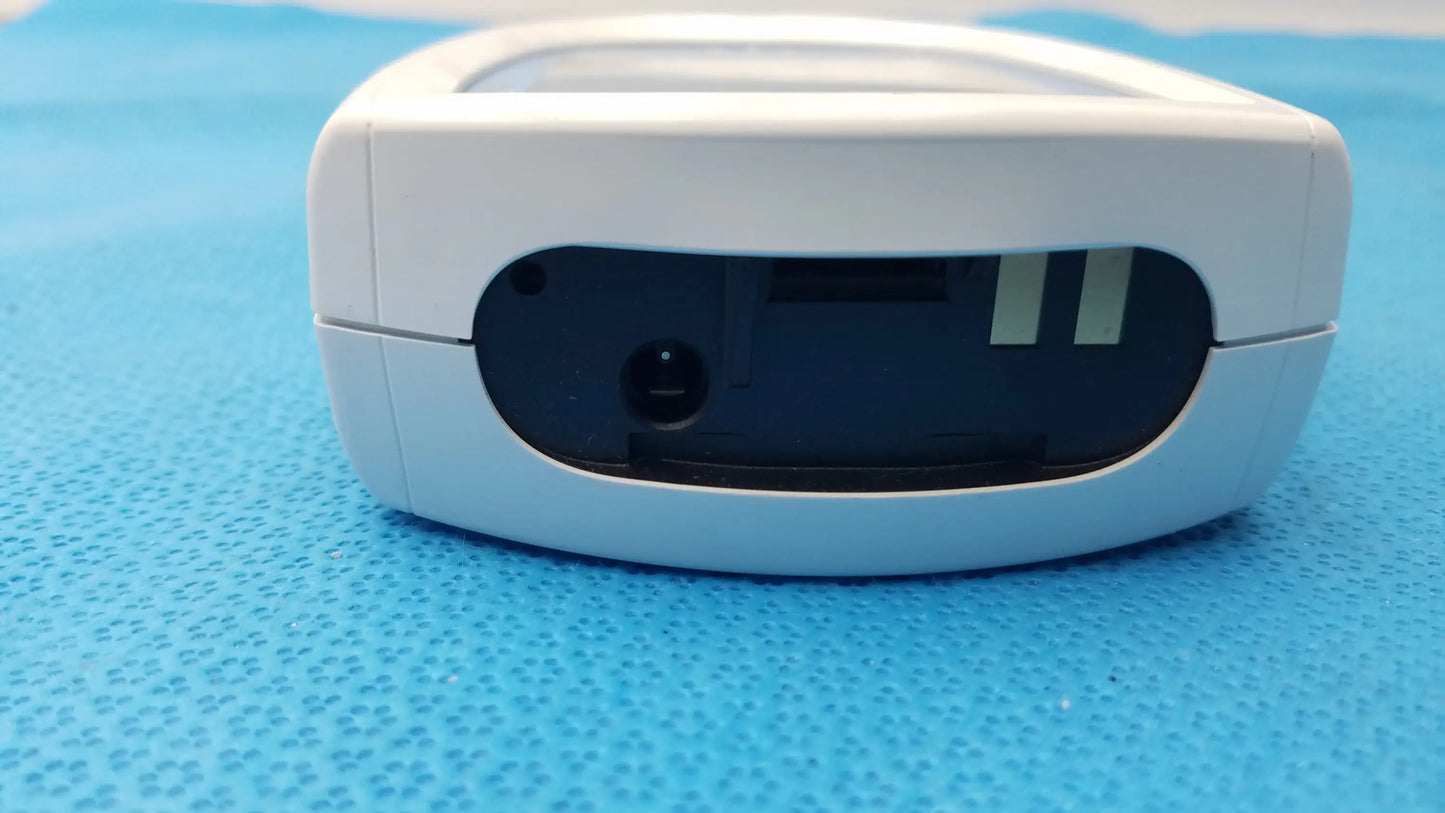 White plastic roche coaguchek xs plus coagulation meter with black panel featuring two slots and a circular port