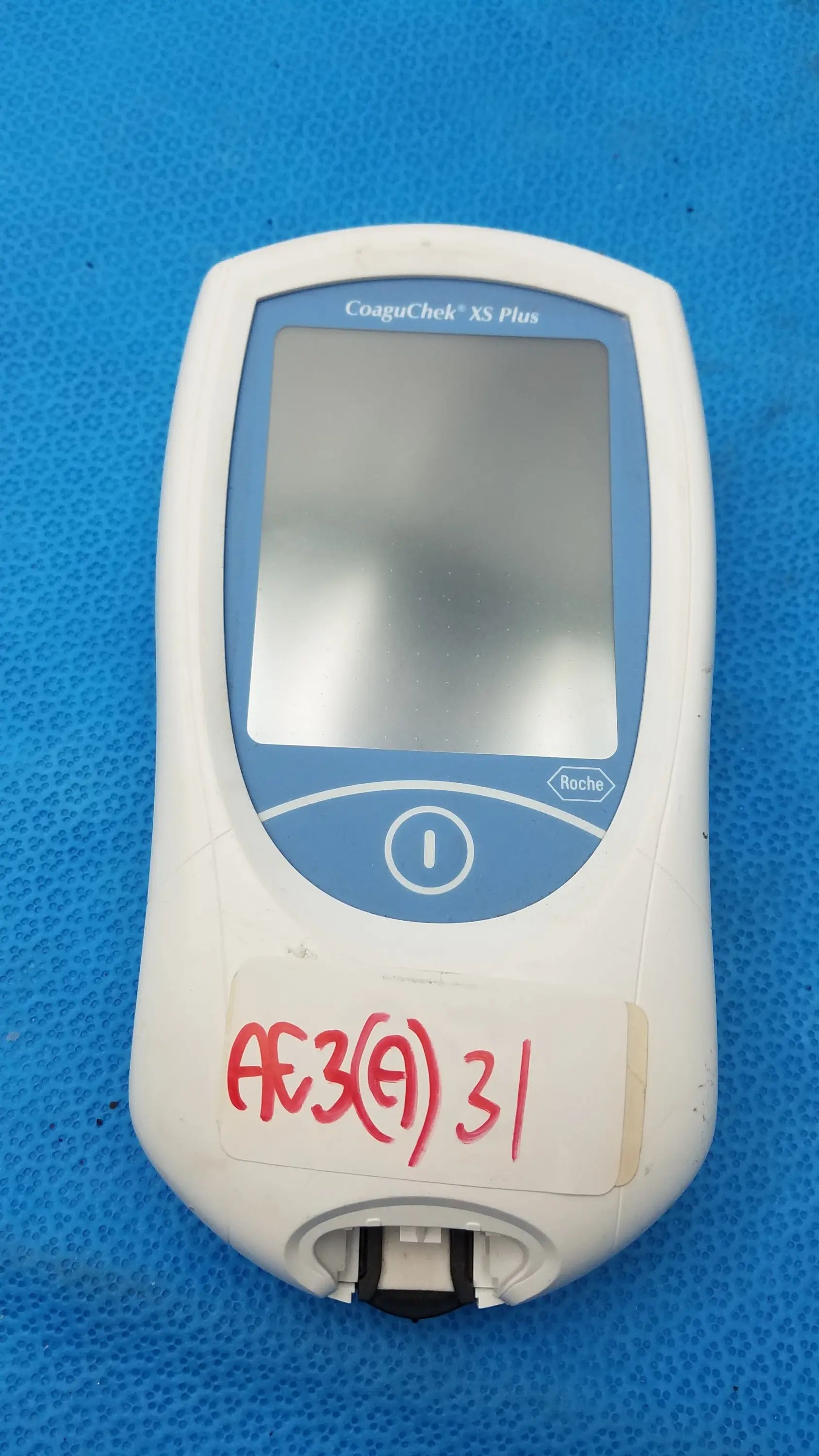 White roche coaguchek xs plus blood coagulation analyzer with blue-accented screen and control button medical equipment
