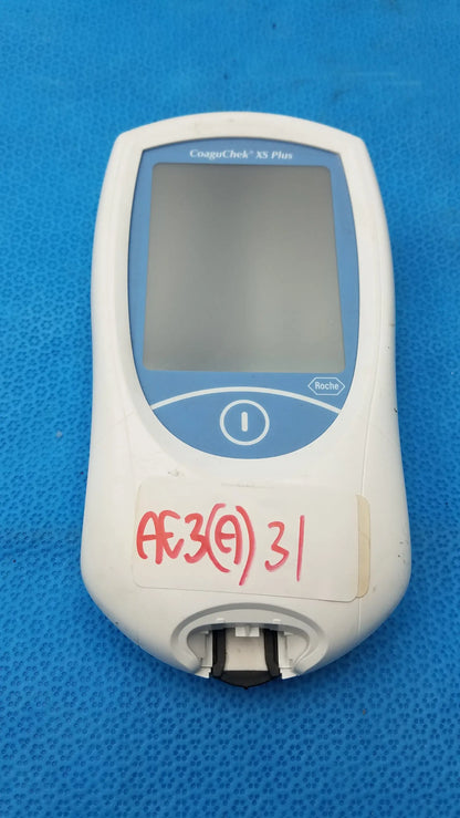 White and blue Roche CoaguChek XS Plus medical equipment with rectangular screen and circular button for coagulation testing