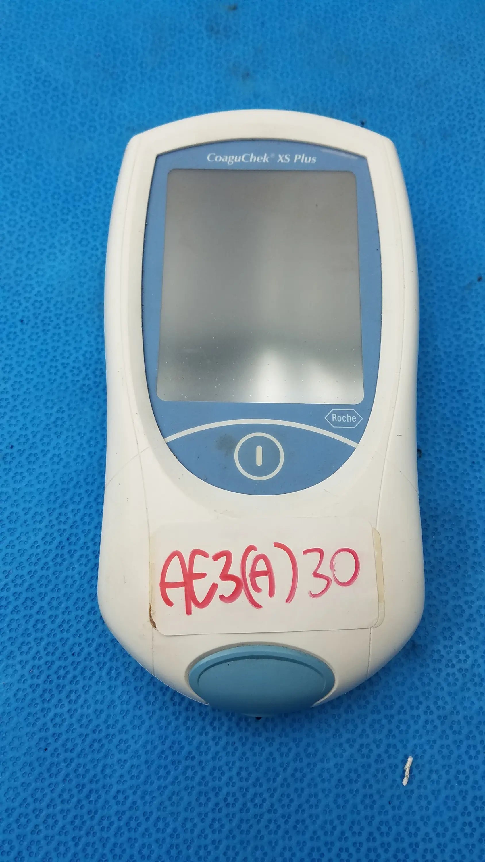 Roche CoaguChek XS Plus coagulation meter in white and blue with a central screen for medical equipment use