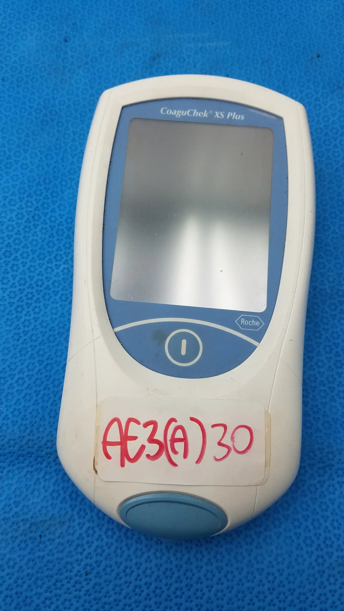 Roche CoaguChek XS Plus coagulation meter in white and blue with rectangular screen and circular button medical equipment