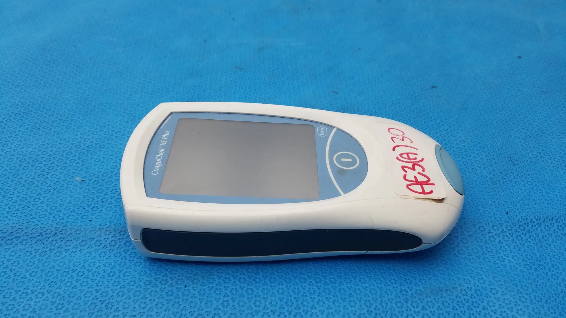 White and gray roche coaguchek xs plus coagulation meter with rectangular screen and circular button medical equipment