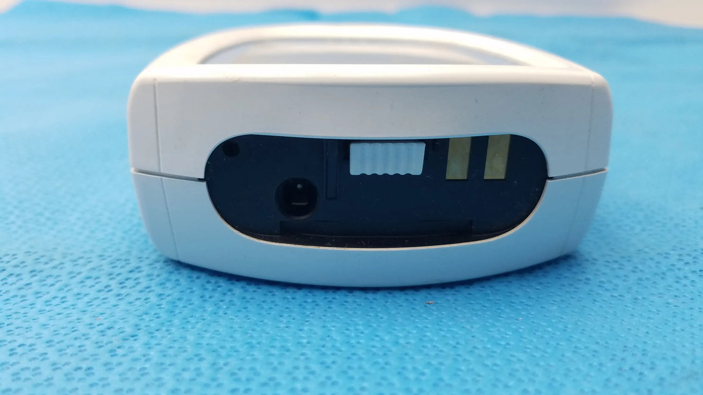 White plastic handheld roche coaguchek xs plus coagulation meter with black sensor slot panel and power button medical equipment