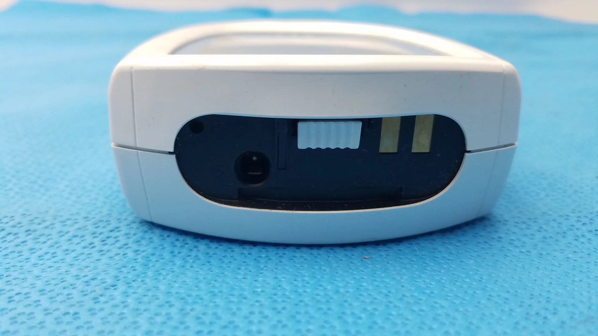 White plastic handheld roche coaguchek xs plus coagulation meter with black sensor slot panel and power button medical equipment