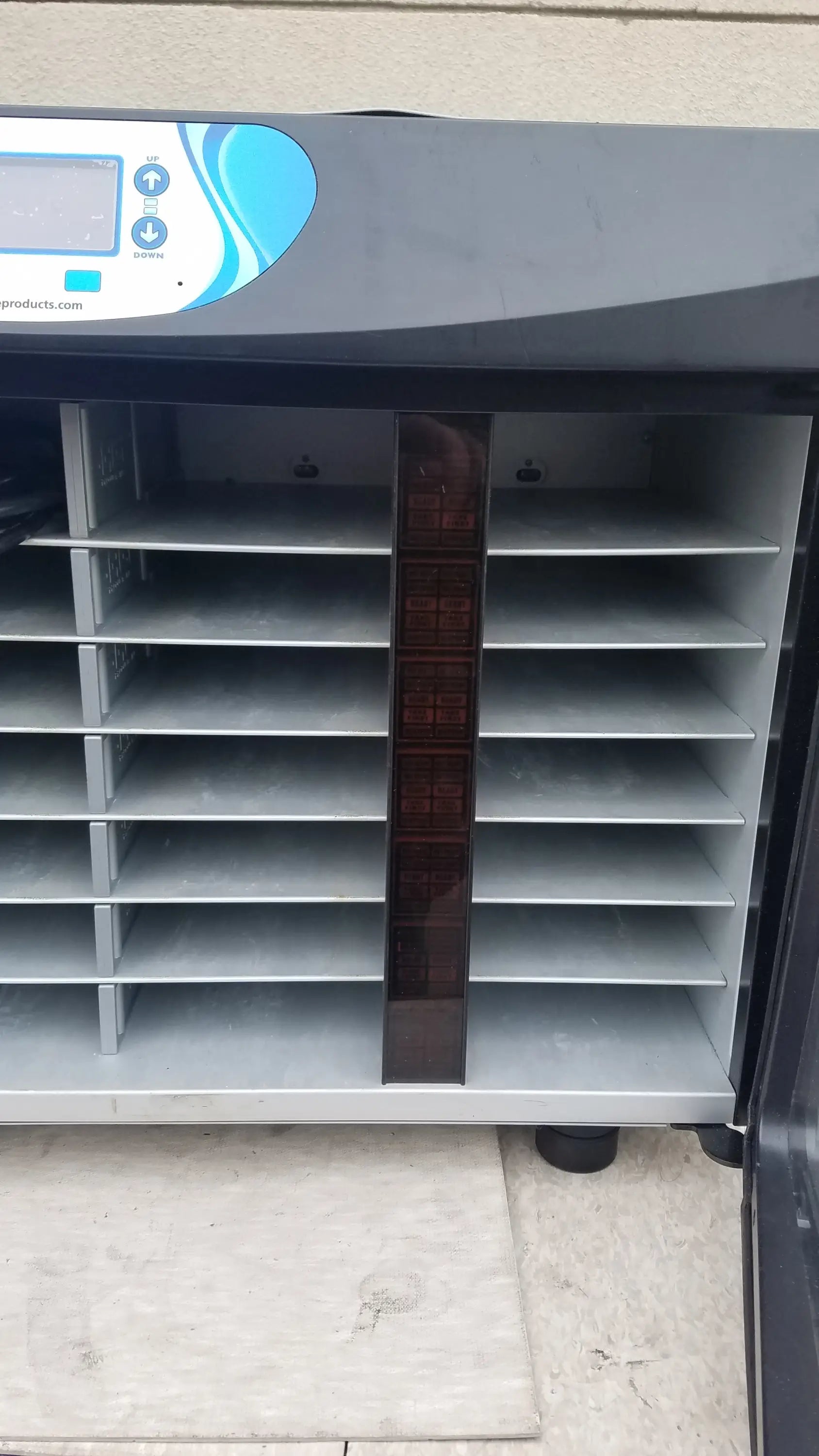Gray plastic incubator with blue and white control panel and adjustable shelves for personal cleansing in medical equipment